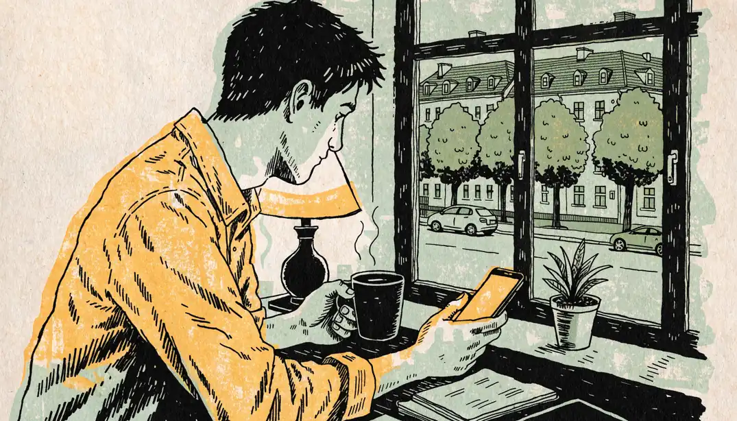 Spieler mit Smartphone und Kaffeetasse am Schreibtisch in Berliner Wohnung