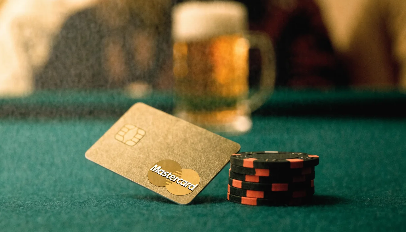 Mastercard-Kreditkarte auf grünem Filz eines Spieltisches mit Casino-Chips